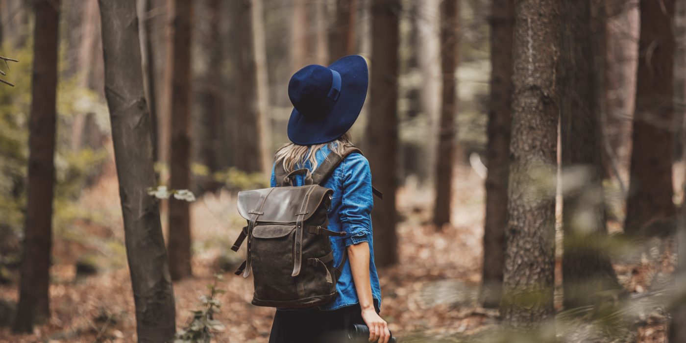 Young woman with binocular and backpack in a forest